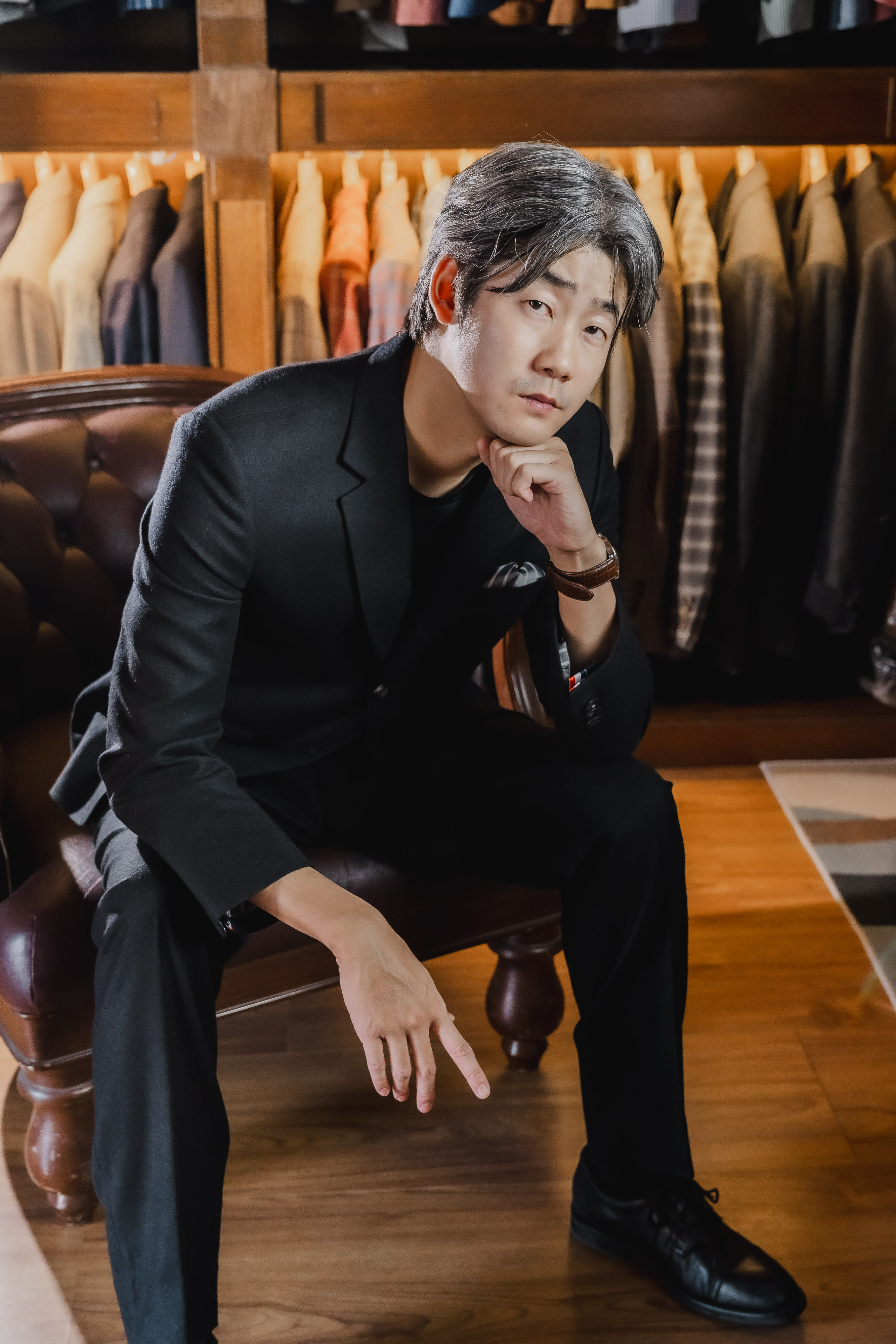 Black suit seated in leather chair